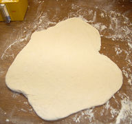 Die Teigportionen leicht auswellen und mit den Handrücken dünn zu einem runden Pizzaboden mit dickerem Rand ausziehen.